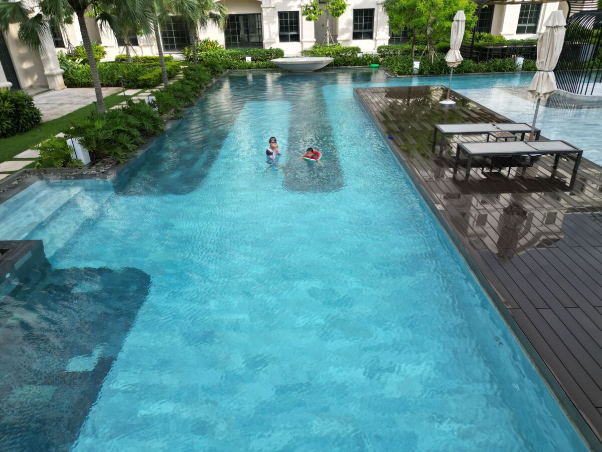 Two children swimming in a resort pool surrounded by lush greenery in Vietnam.