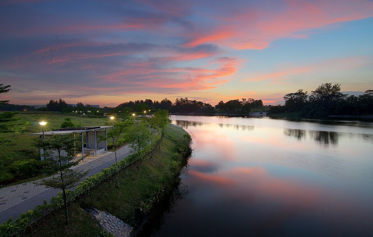 Pink and orange sunset reflected on the lake with riverside path and shelter at Punggol Waterway Park