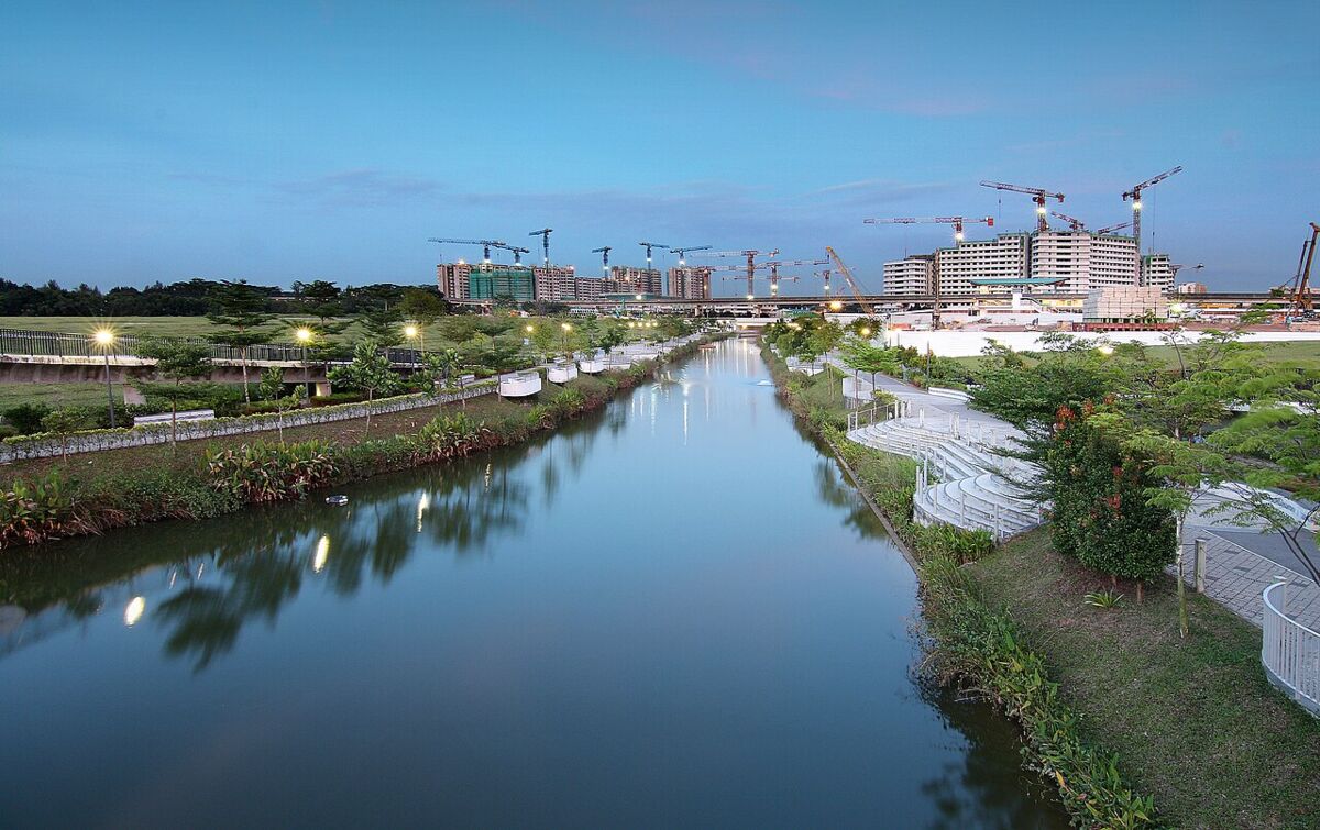 Wide dusk view of the Punggol waterway lined with greenery and reflections of the surrounding town