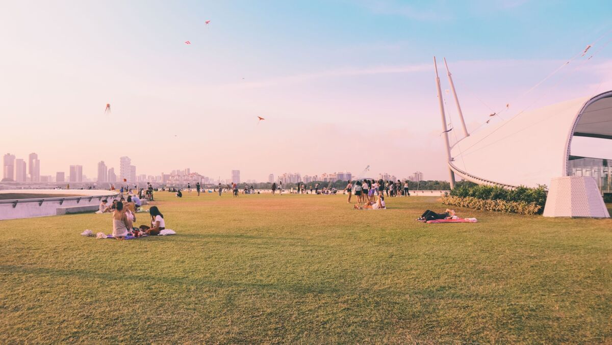 Groups of people relaxing and flying kites at Marina Barrage in Singapore.