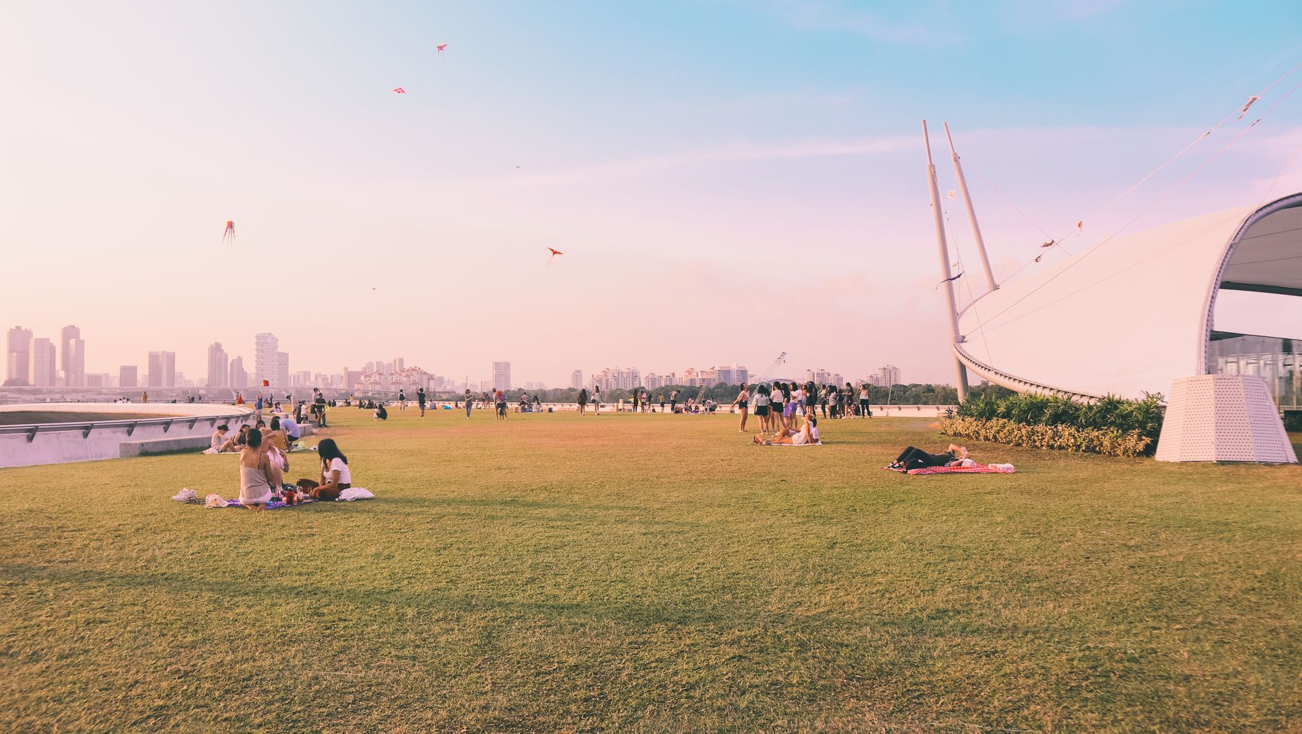 Groups of people relaxing and flying kites at Marina Barrage in Singapore.