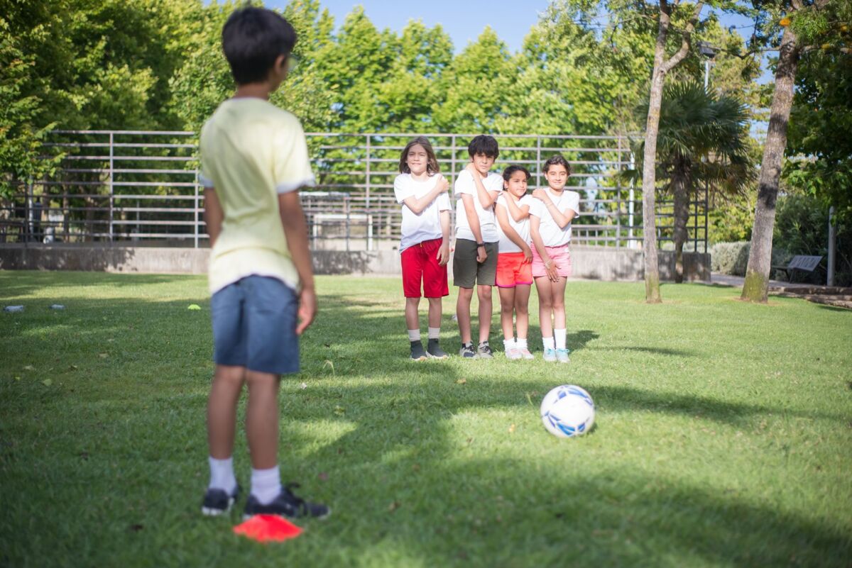 A group of kids enjoy a soccer game outdoors in a sunny park setting.