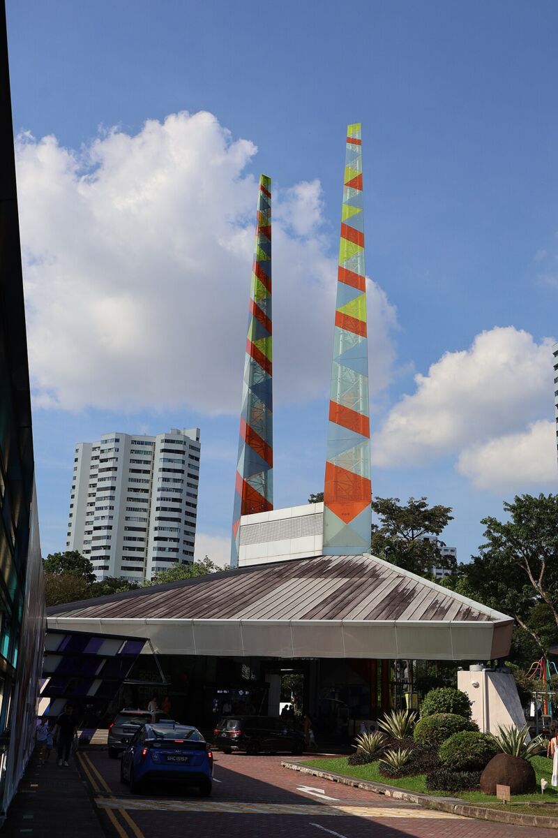 Entrance to Science Centre Singapore with its colorful twin pyramid towers above the drop-off canopy