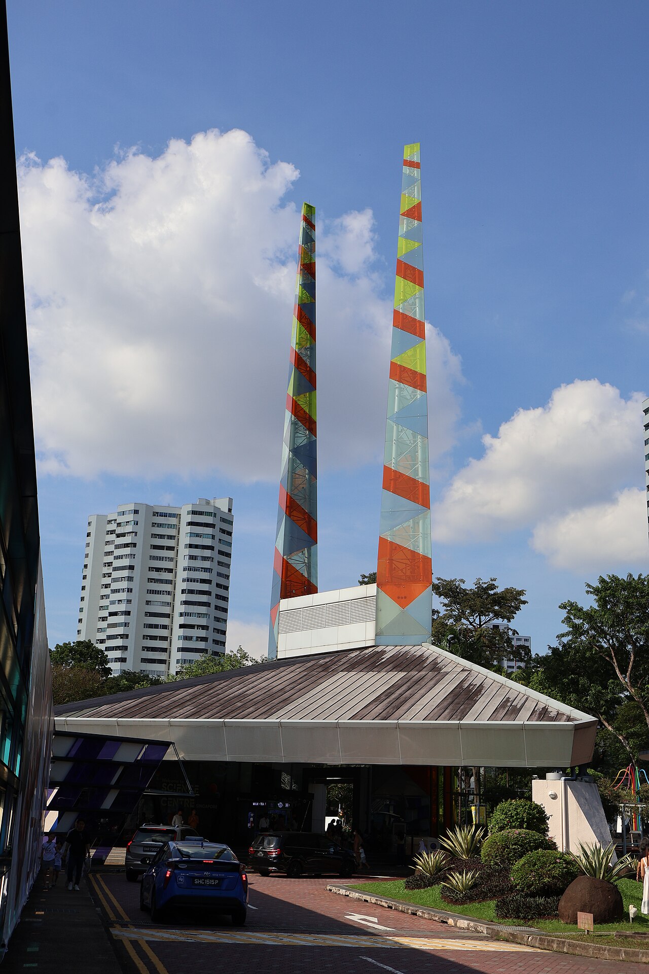 Entrance to Science Centre Singapore with its colorful twin pyramid towers above the drop-off canopy