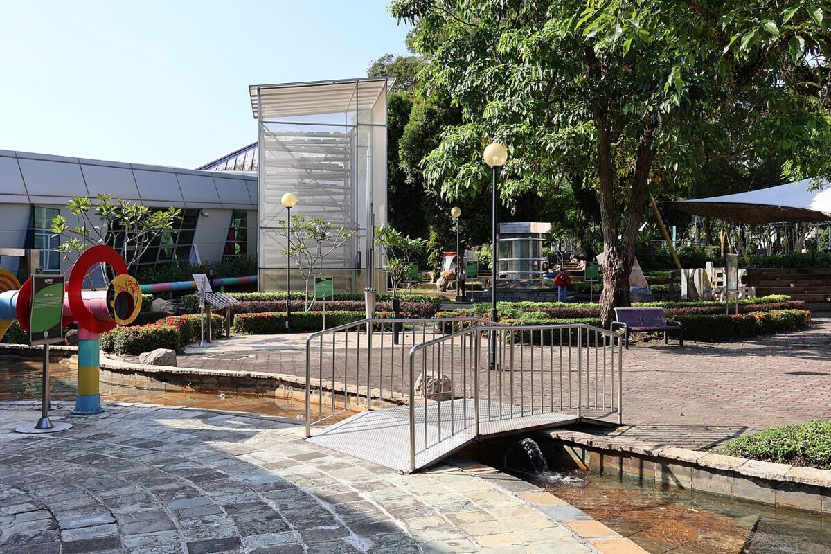 The outdoor Kinetic Garden at Science Centre Singapore with colorful science play structures and a stream