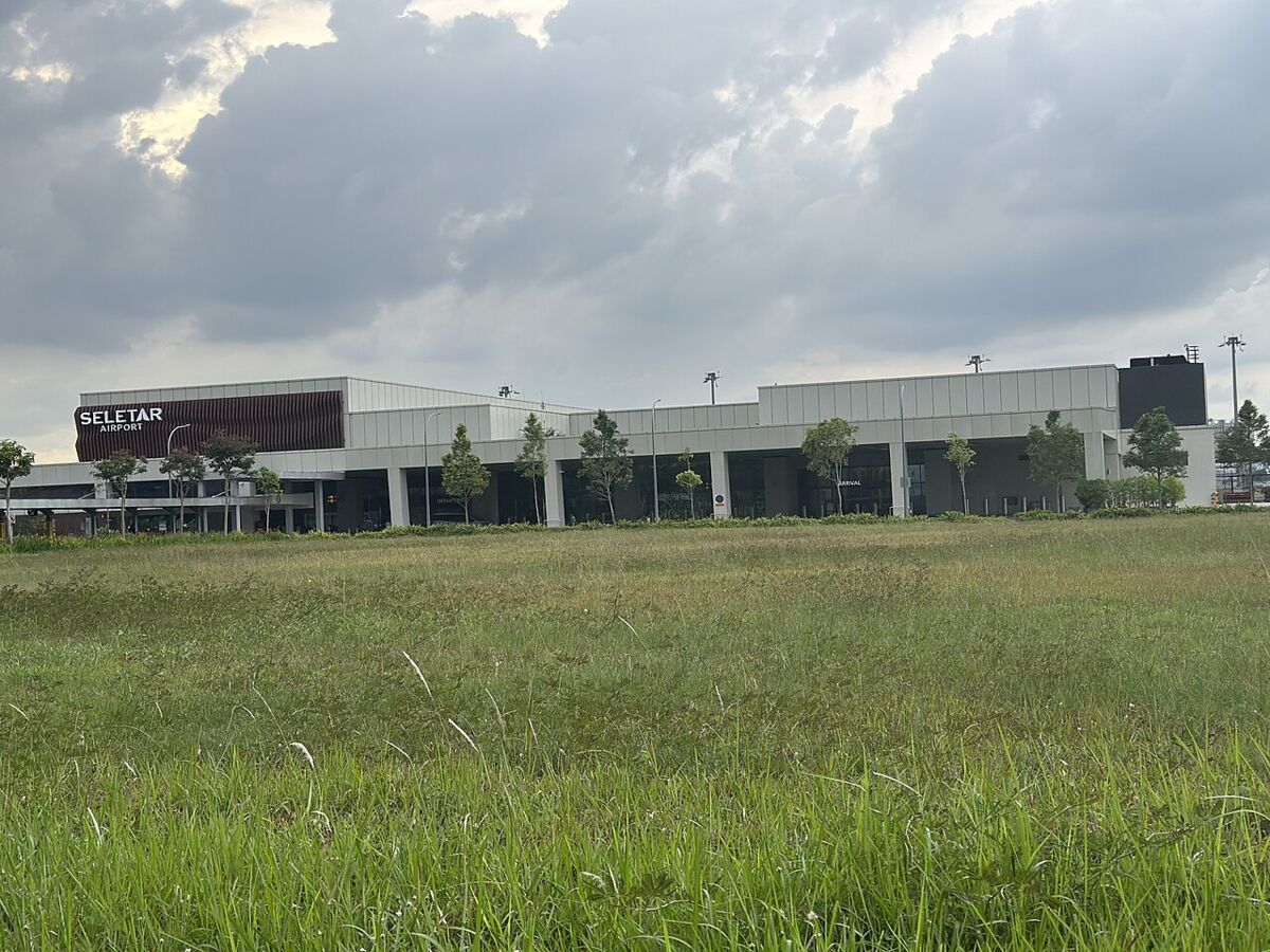 Seletar Airport terminal building with its signage seen across an open grass field at Seletar Aerospace Park