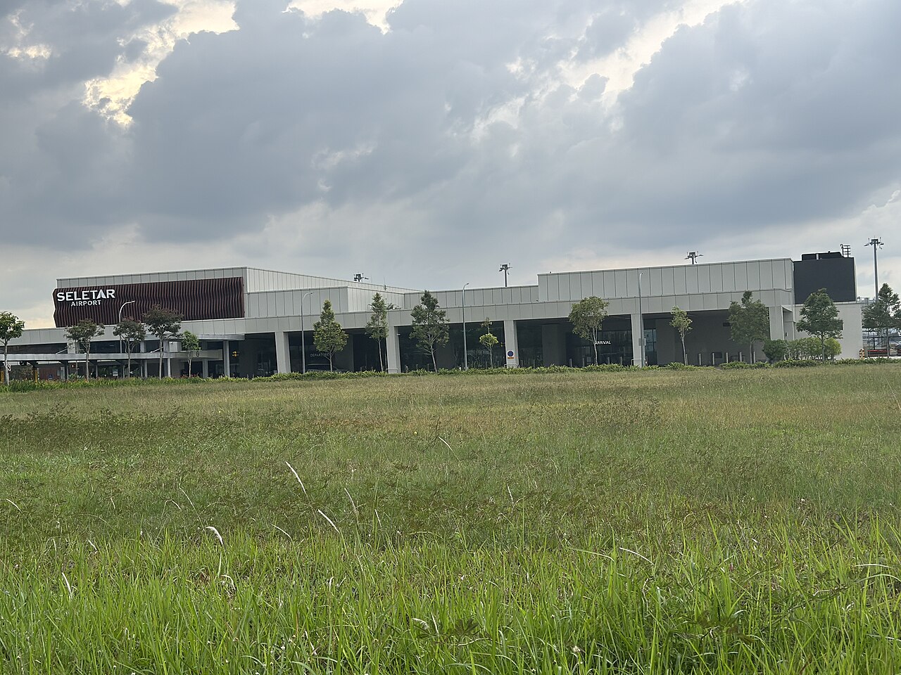 Seletar Airport terminal building with its signage seen across an open grass field at Seletar Aerospace Park