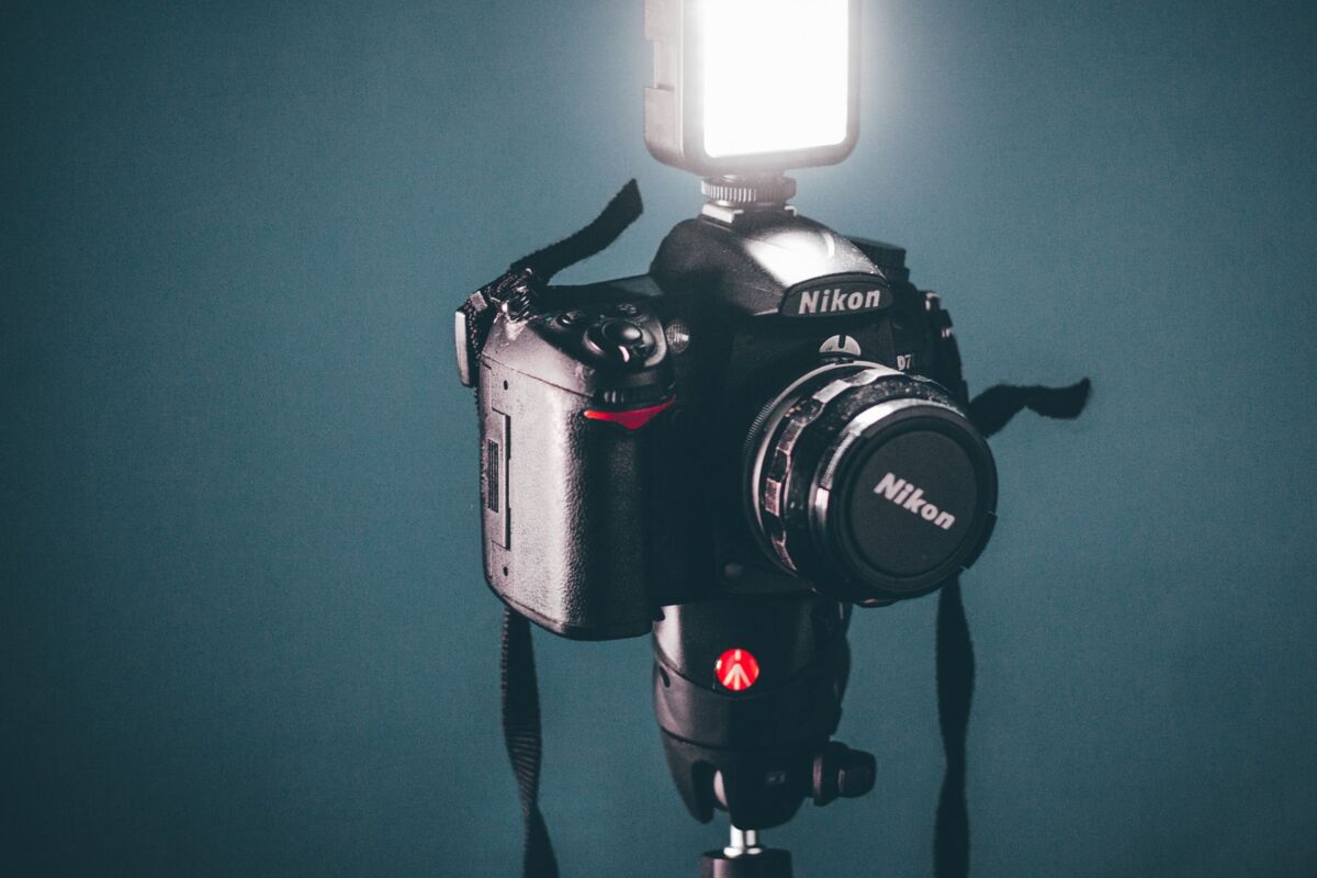 Close-up of a DSLR camera with a flash attachment on a tripod, perfect for photography setups.