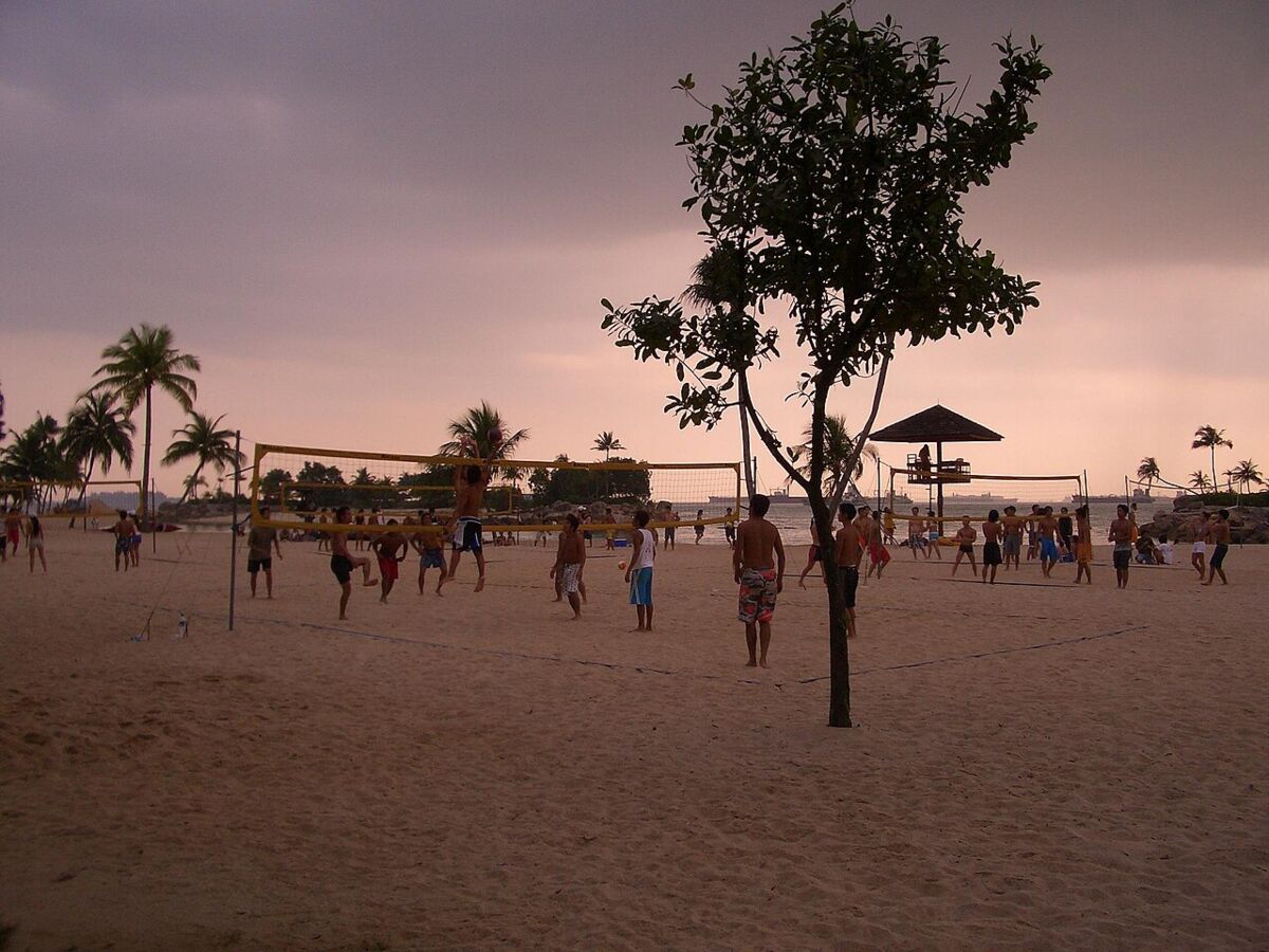People playing beach volleyball on the sand at Sentosa at dusk