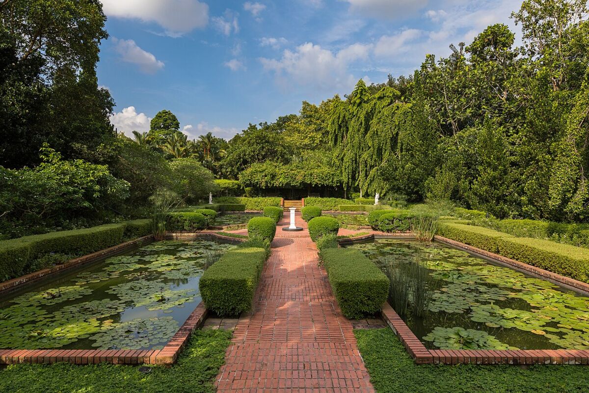 Symmetrical brick path flanked by lily ponds and clipped hedges at the Sundial Garden, Singapore Botanic Gardens
