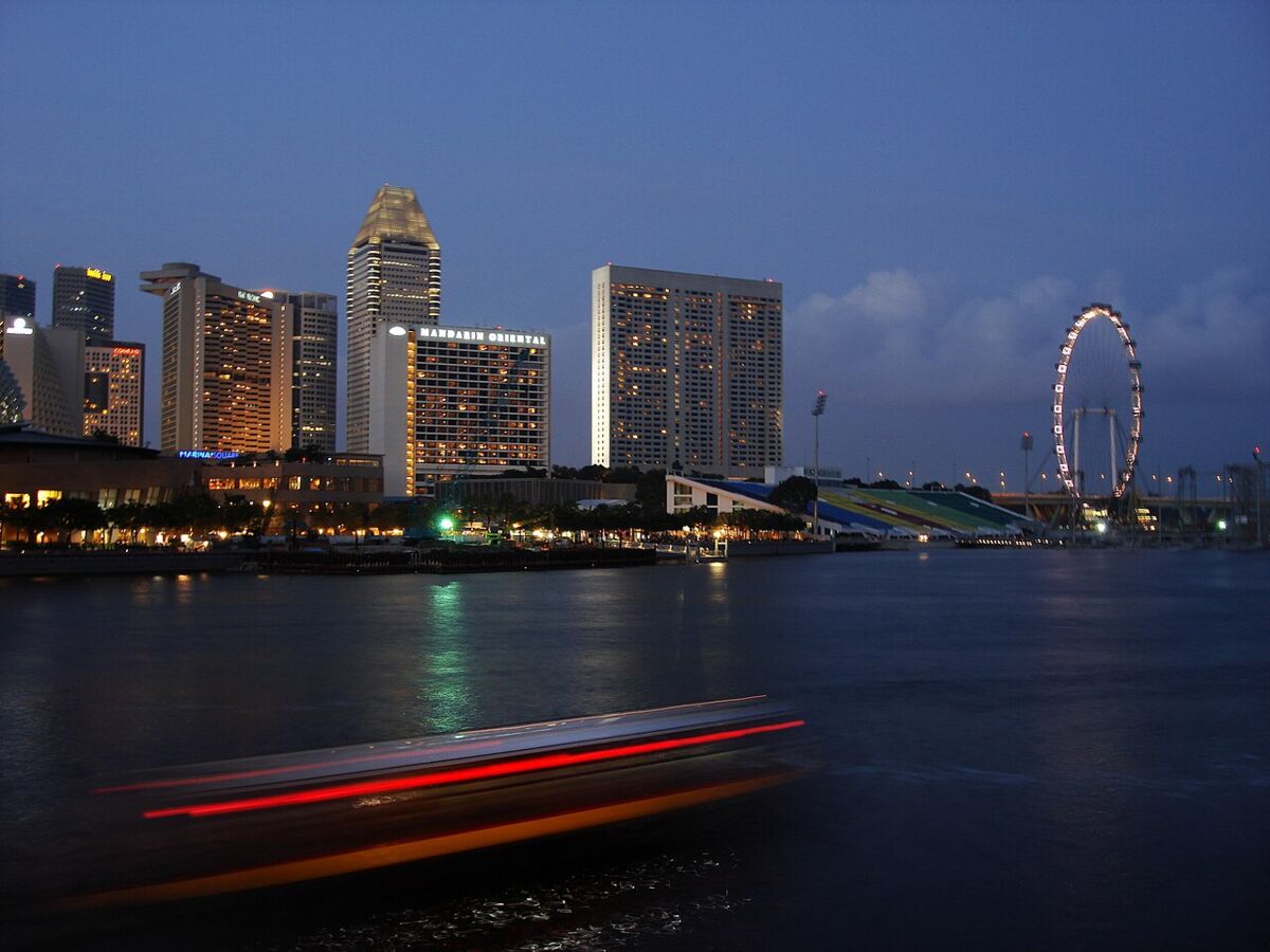 The Singapore Flyer lit up at dusk across Marina Bay with the city skyline