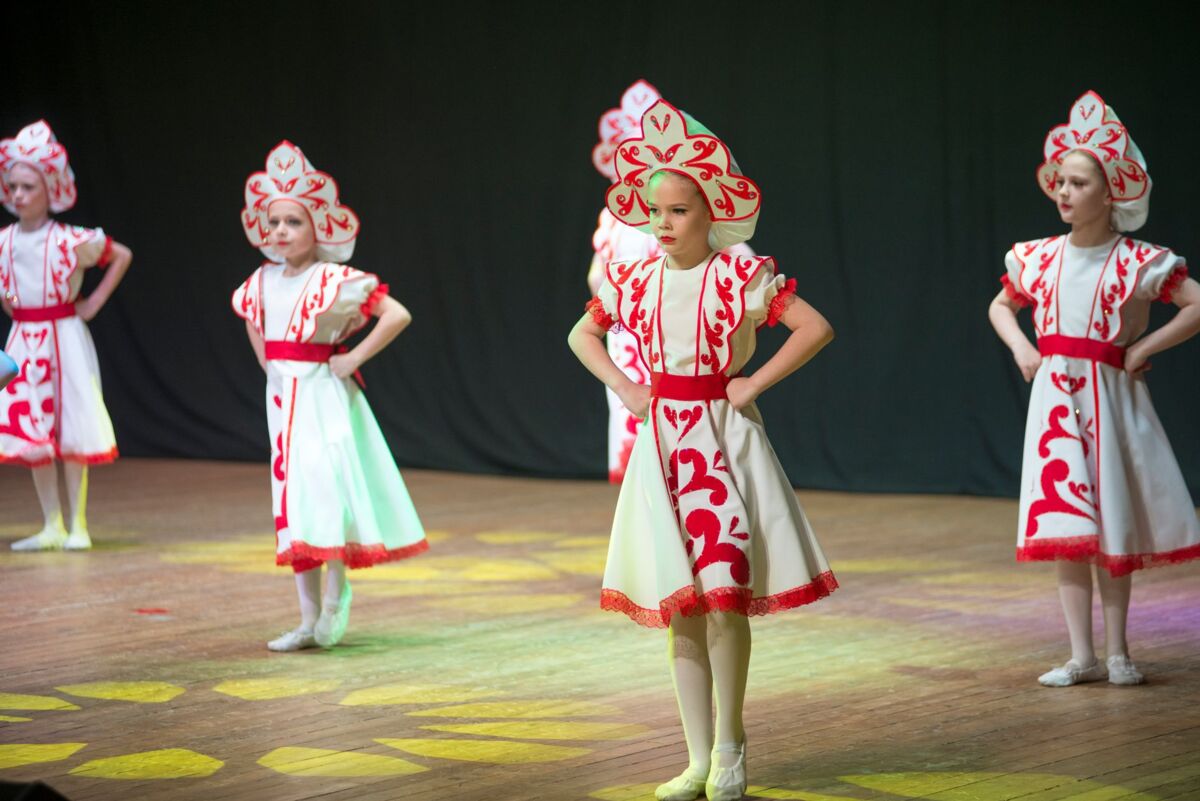 Young girls in traditional attire performing a cultural dance on stage.