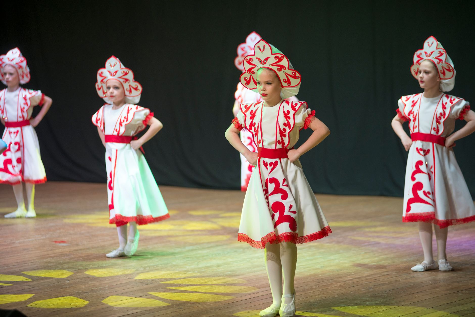 Young girls in traditional attire performing a cultural dance on stage.