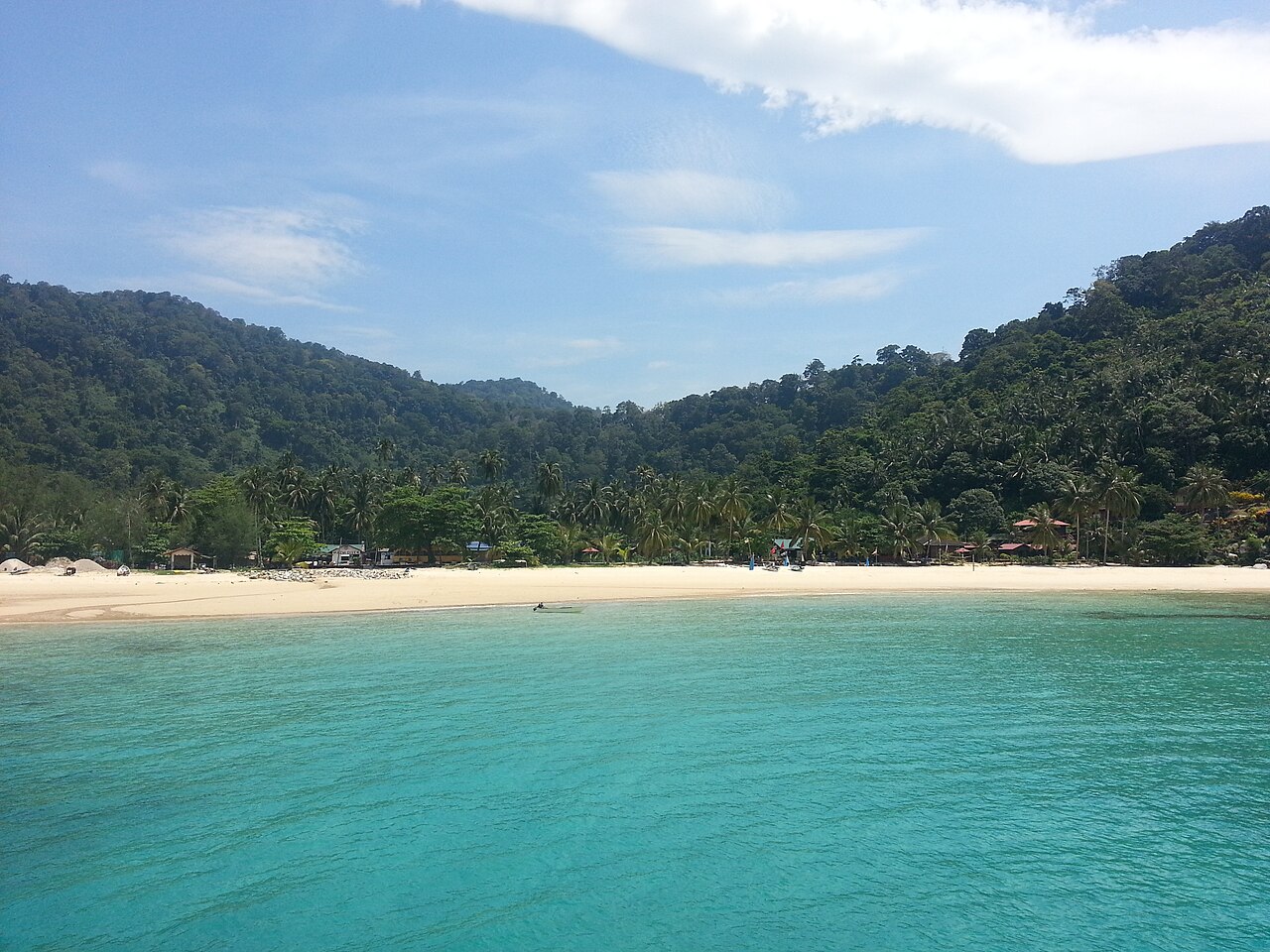 Turquoise water and white sand at Salang beach on Tioman Island, backed by jungle hills and palm trees