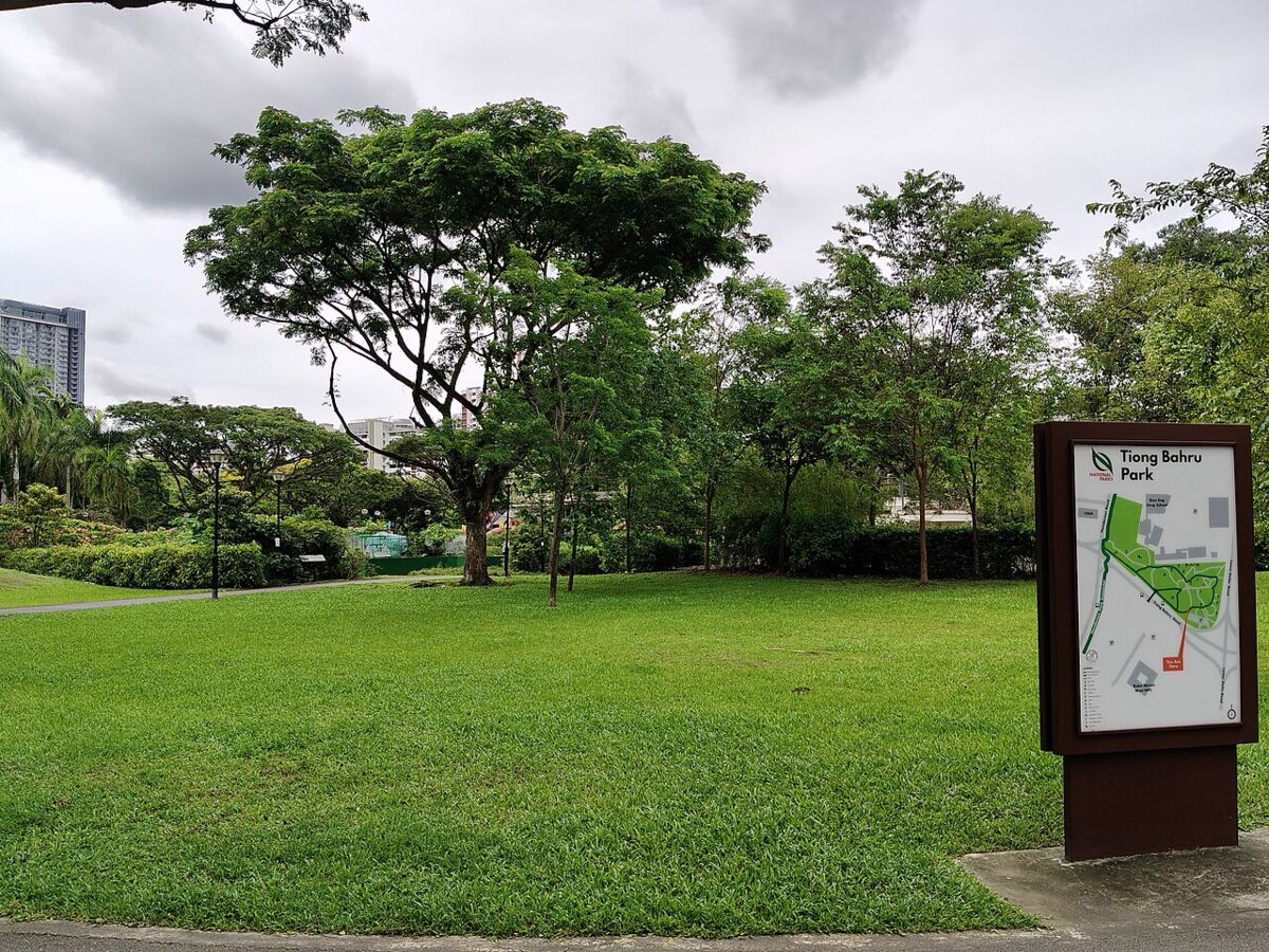 Open lawn and shade trees at Tiong Bahru Park with an estate map signboard