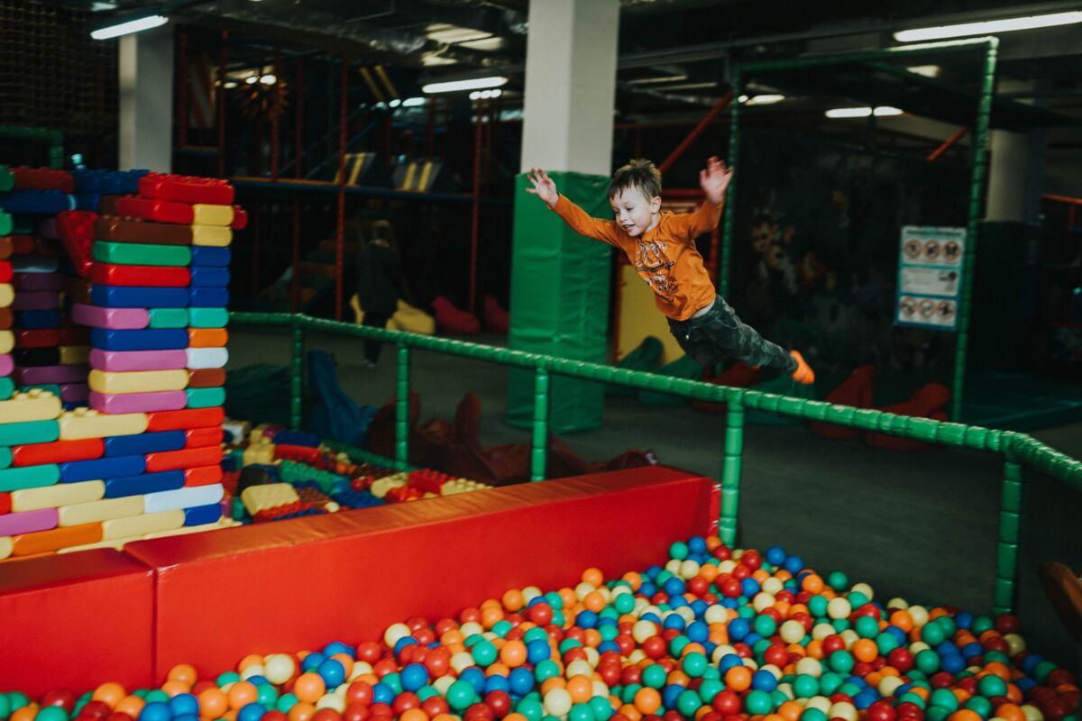A joyful child jumps into a colorful ball pit at an indoor playground, capturing fun and excitement.