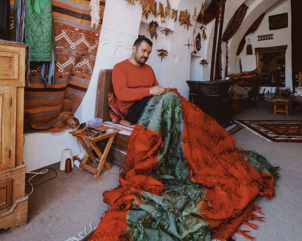 A skilled craftsman creating vibrant handmade textiles in a cozy, traditional workshop.