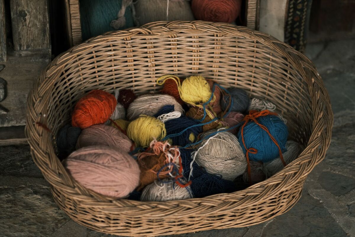 A variety of colorful yarns in a woven basket, perfect for knitting or crafts.