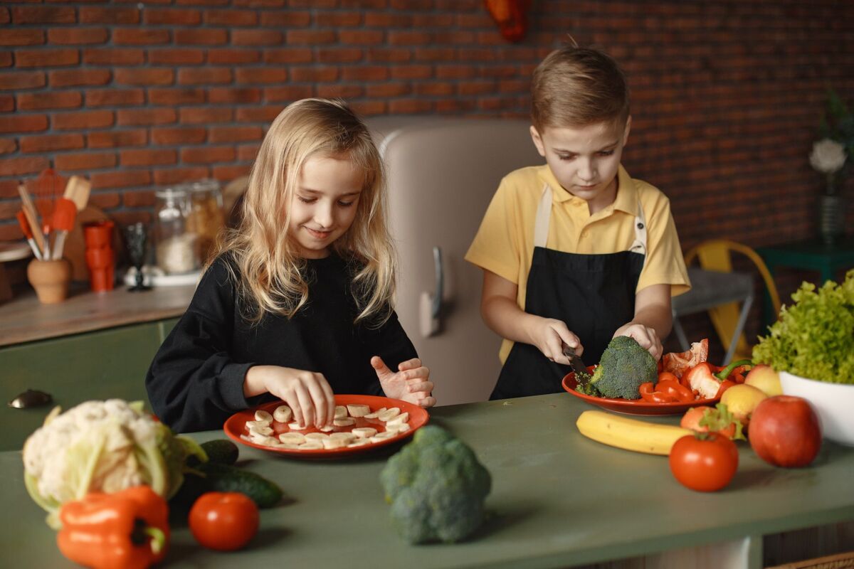 Two kids having fun preparing a healthy meal with fresh ingredients indoors.