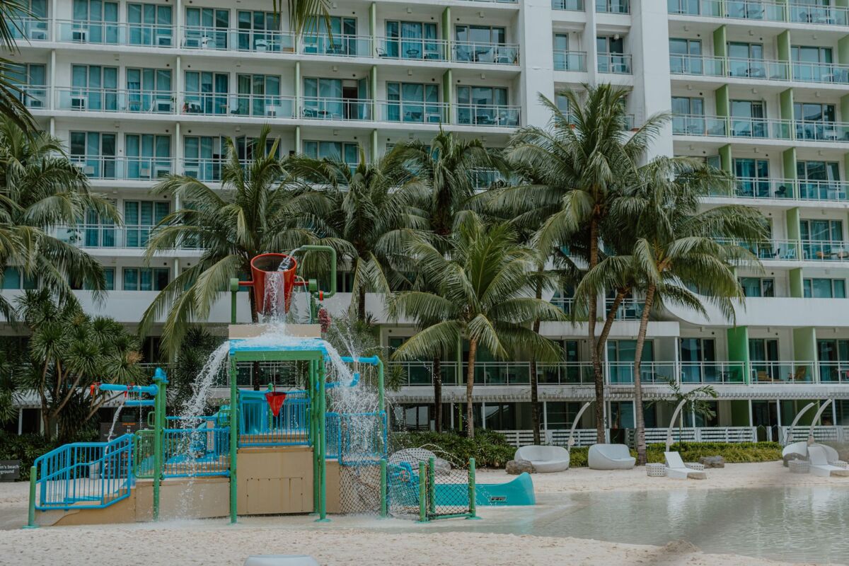 A vibrant splash playground beneath palm trees at a beachfront resort.
