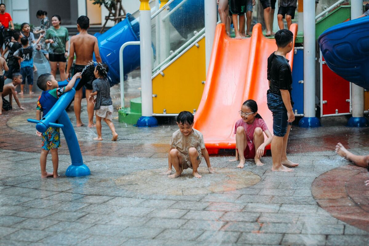 Group of children having fun at a water park in summer, sliding and playing in colorful water playground.