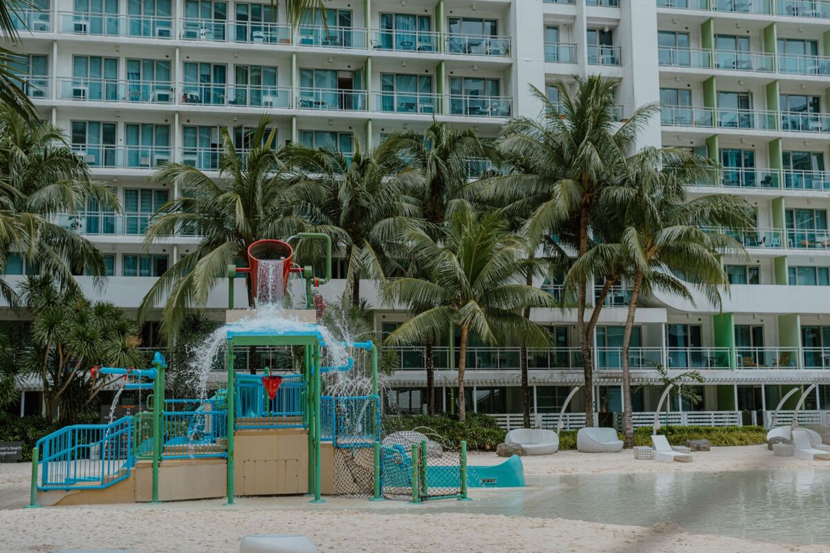 A vibrant children's water play area at a tropical resort surrounded by palm trees.
