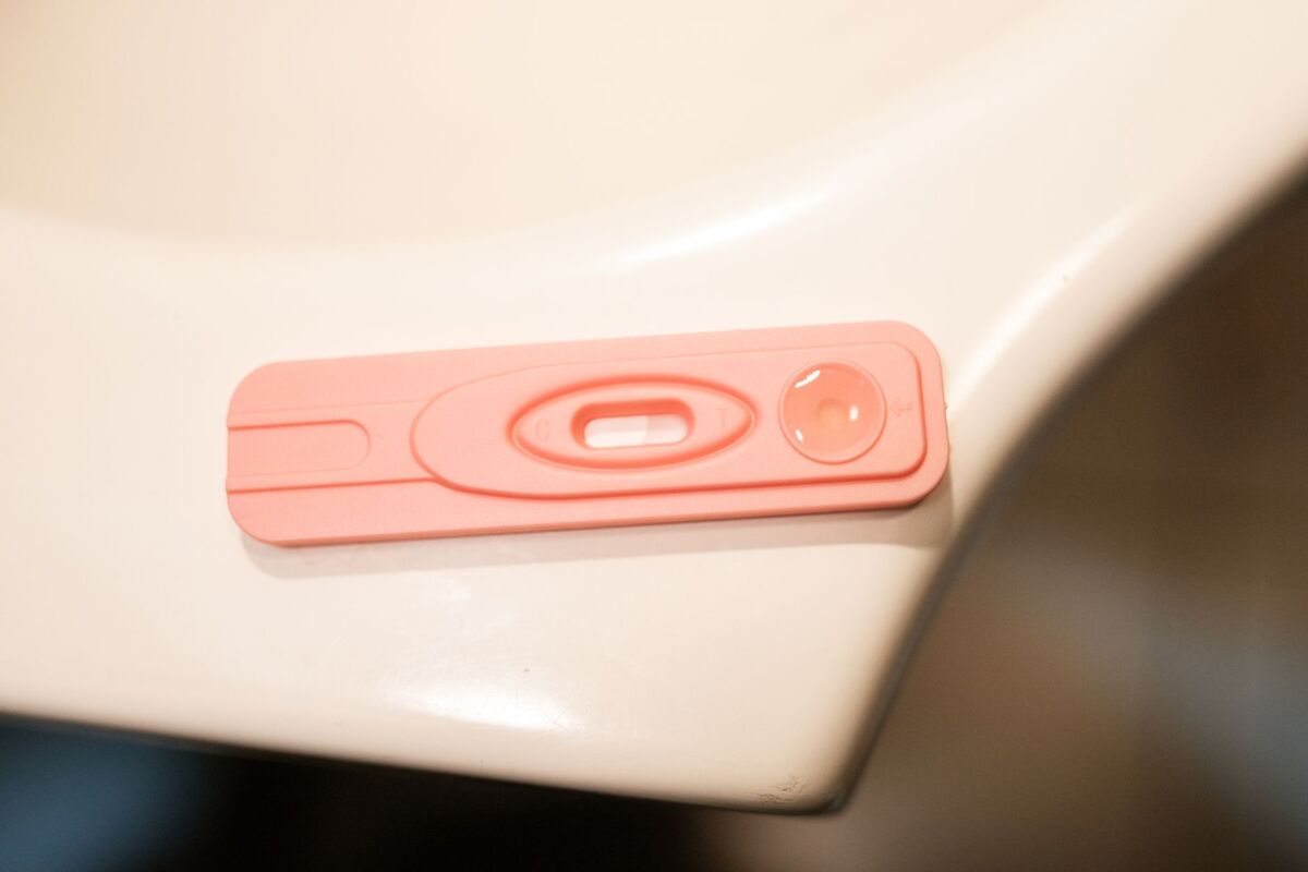A detailed close-up of a pink pregnancy test kit on a white surface.