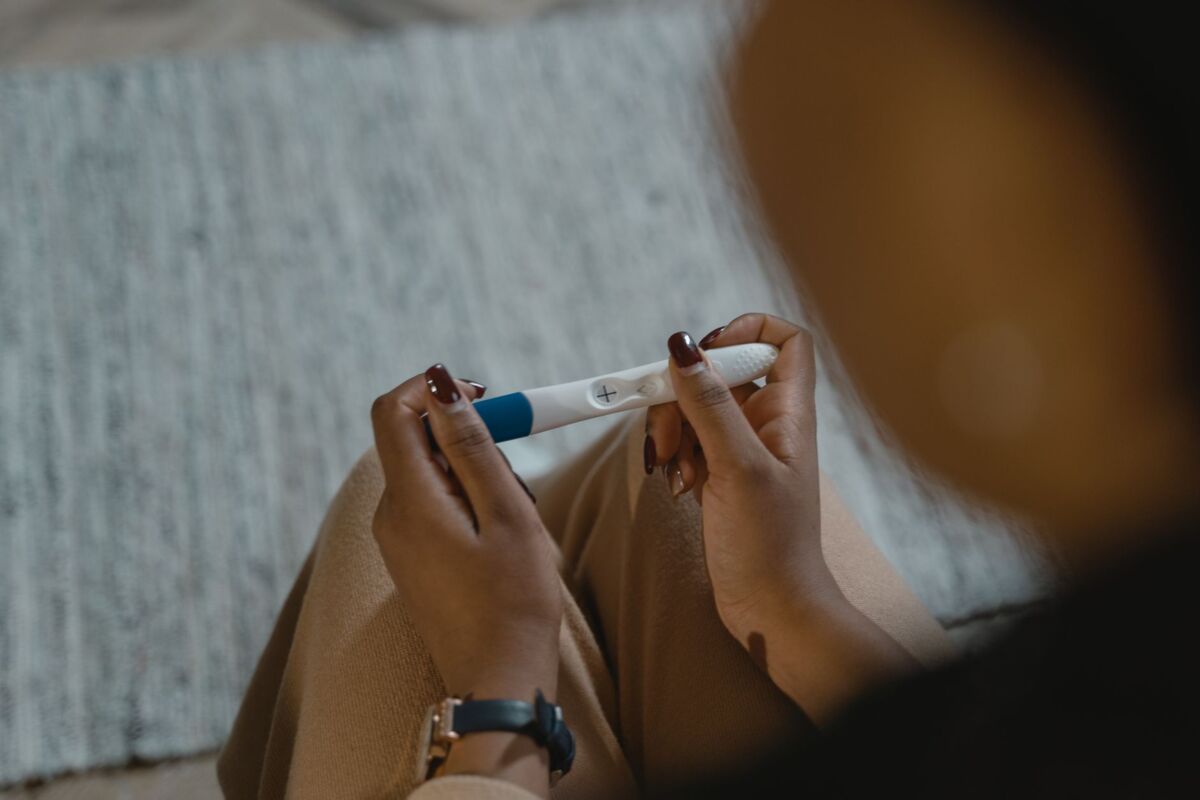 Close-up of a woman holding a positive pregnancy test with a plus sign, symbolizing new beginnings.
